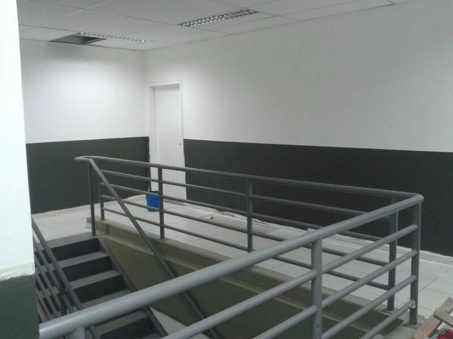 Vista superior do mezanino com guarda-corpo metálico, paredes pintadas e iluminação instalada