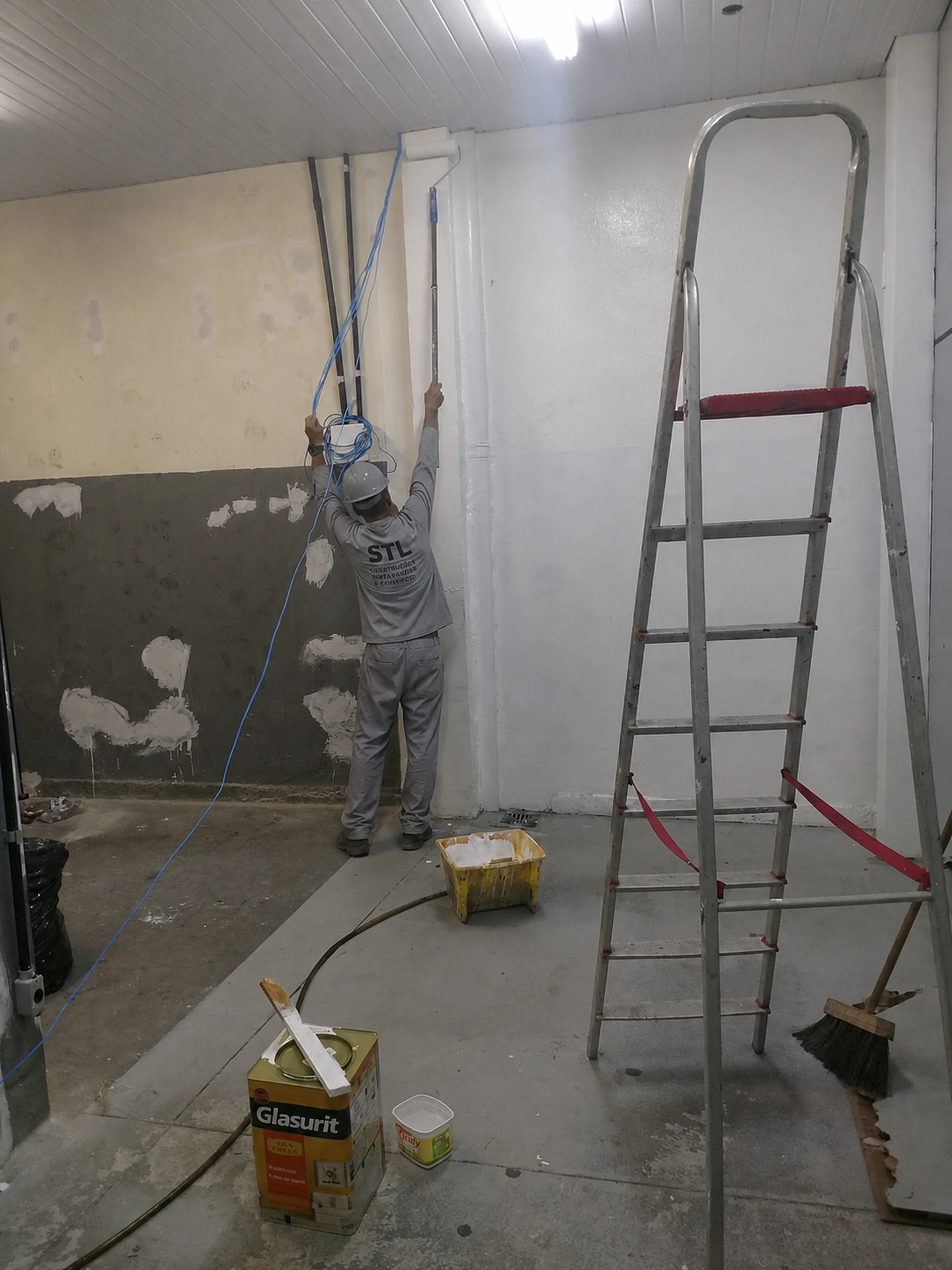 Trabalhador aplicando pintura em parede durante reforma do escritório