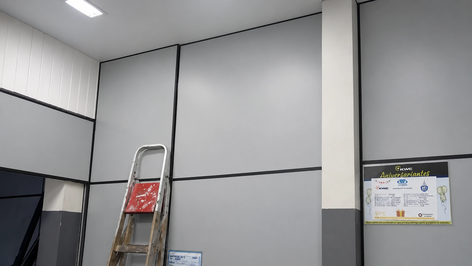 Sala com forro instalado, paredes com pintura avançada e escada de trabalho