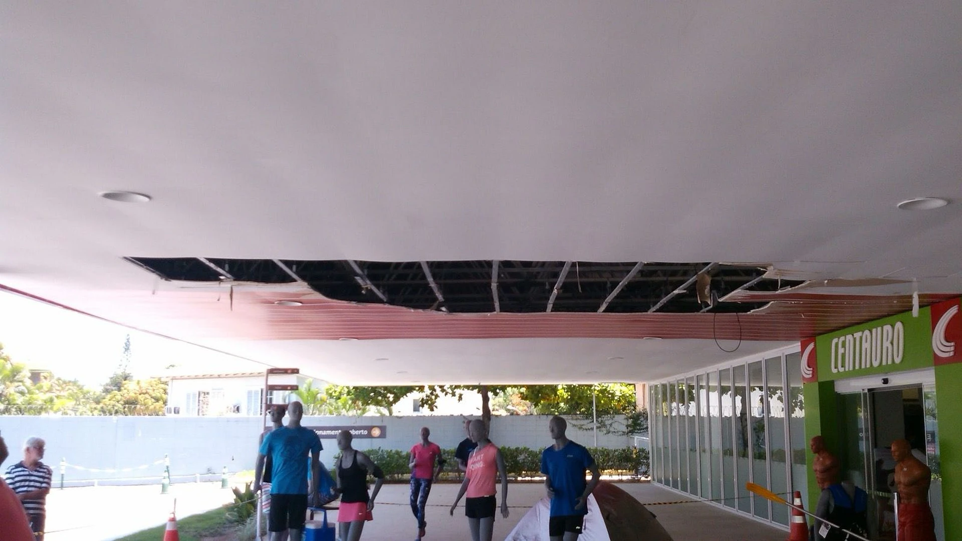 Vista da passarela com abertura no forro e pedestres circulando abaixo
