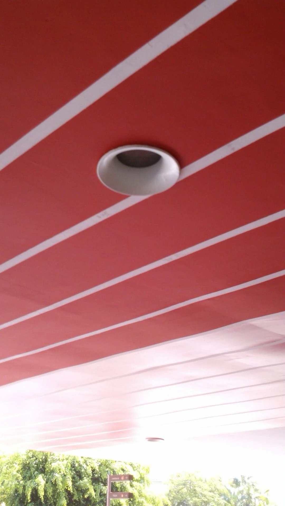 Detalhe do forro acabado em vermelho com faixas brancas e luminária embutida