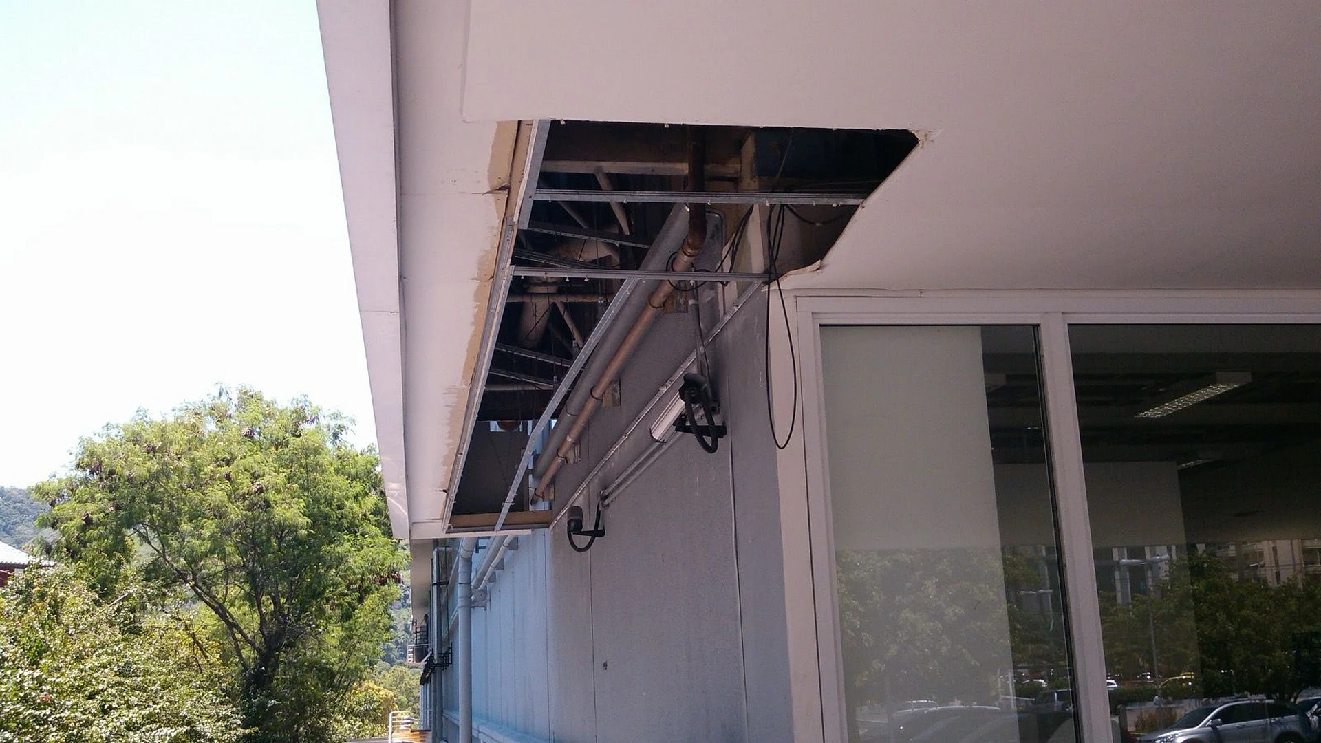 Fachada externa com abertura na marquise e cabeamentos expostos antes da intervenção