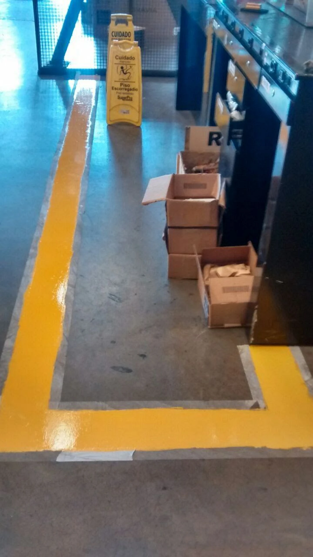Faixa de demarcação amarela em corredor do centro de distribuição com sinalização de piso úmido