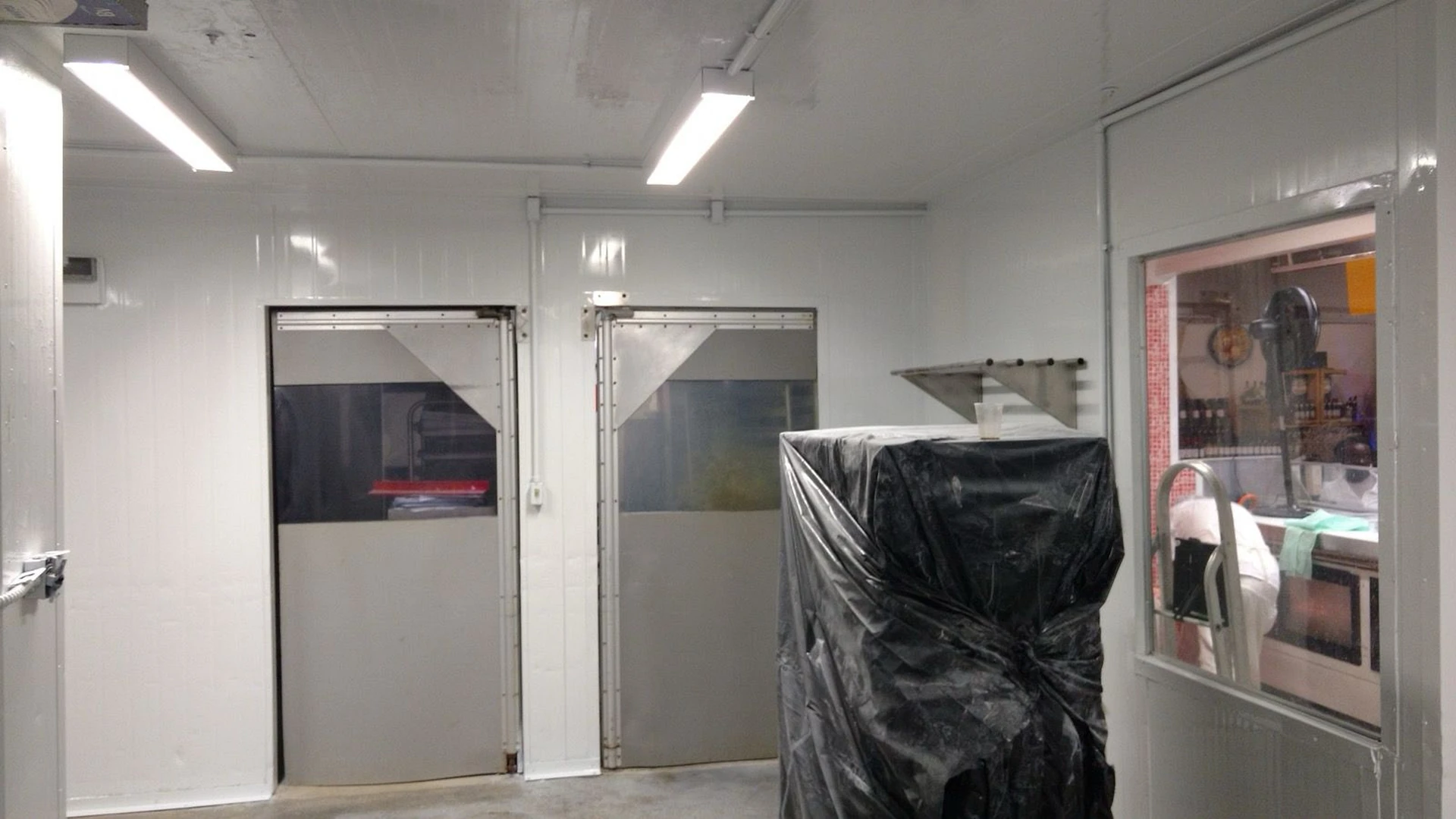 Interior do setor com duas portas de câmara frigorífica em fase de instalação e ajuste