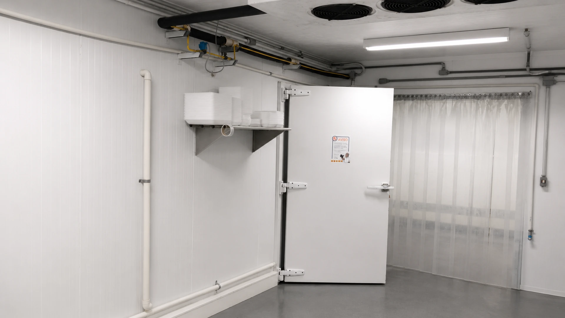Interior da câmara frigorífica concluída com porta articulada, cortina de PVC e sistema de refrigeração
