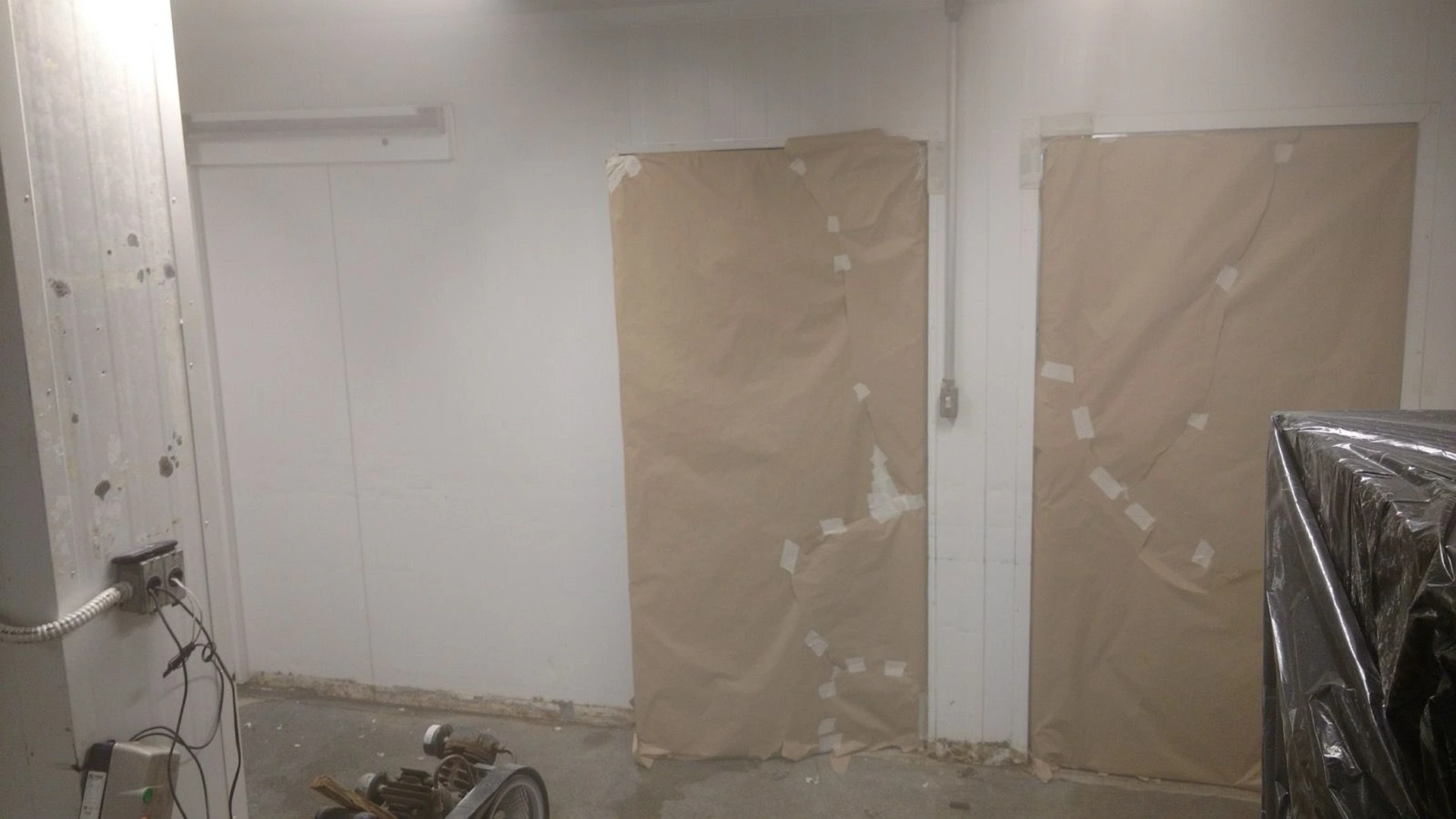 Portas e equipamentos protegidos com papelão e plástico antes da aplicação de pintura